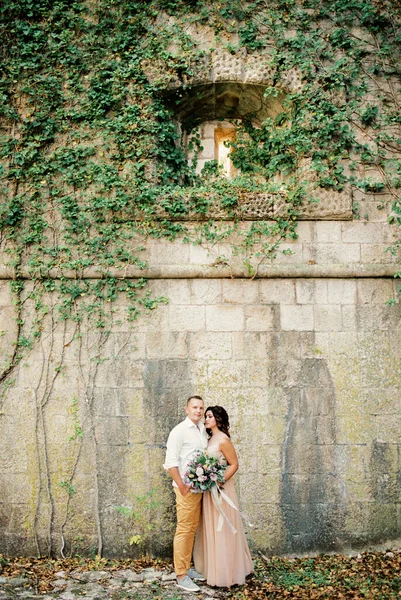 Νύφη Και Γαμπρός Στέκονται Κοντά Στον Πέτρινο Τοίχο Του Φρουρίου — Φωτογραφία Αρχείου