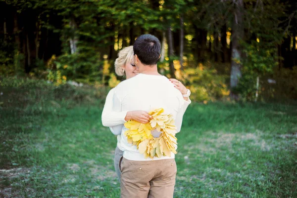 男は黄色の葉の花輪を手に女性を抱擁する バックビュー 高品質の写真 — ストック写真