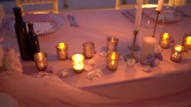 Çiçeklerle döşenmiş bir masada şamdanlarda mum yakmak. Yüksek kaliteli FullHD görüntüler