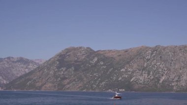 Zevk teknesi dağların arka planına karşı denizde yüzüyor. Yüksek kaliteli FullHD görüntüler