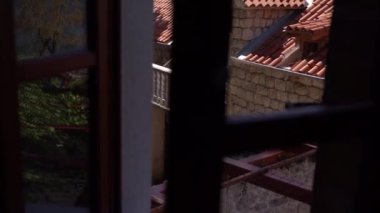 Kırmızı çatılı taş bir evin ahşap balkonunun penceresinden bak. Yüksek kaliteli FullHD görüntüler