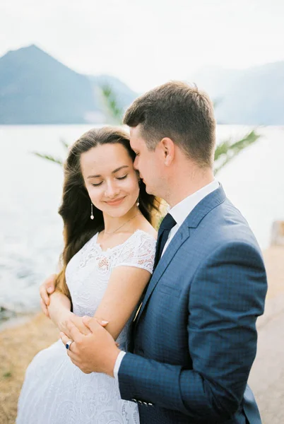 Groom Abraça Noiva Que Fechou Olhos Pelos Ombros Praia Retrato — Fotografia de Stock