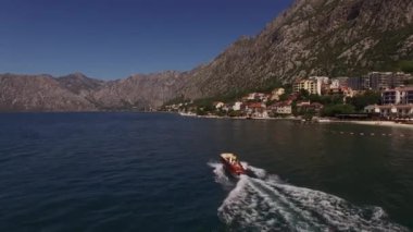 Tekne, sahil boyunca dağların arka planına doğru yelken açıyor. Yüksek kalite 4k görüntü