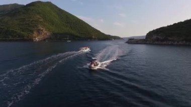 Şişme bir tekne, turistleri yeşil dağların arka planına karşı denizden geçirir. Yüksek kaliteli FullHD görüntüler