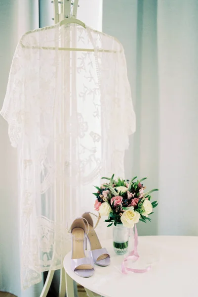 蕾丝袍挂在桌子旁边的衣架上 上面有一束鲜花 高质量的照片 — 图库照片