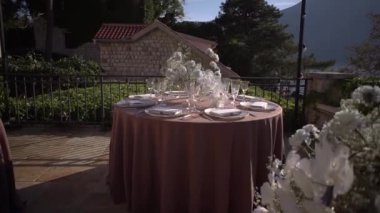 Terasta, çelenklerin altında ampullü şölen masaları. Yüksek kaliteli FullHD görüntüler