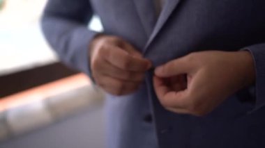 Damat ceketini ilikliyor ve gömleğini düzeltiyor. Yüksek kaliteli FullHD görüntüler