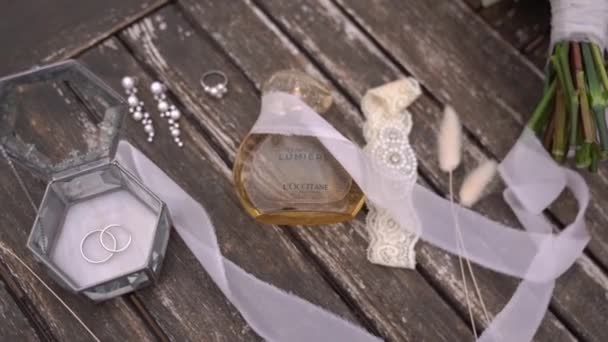 风在一瓶香水和一个装有戒指的盒子旁边的花束上吹着一条白色的缎带 优质Fullhd影片 — 图库视频影像
