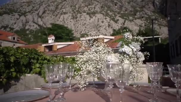 Vas Dengan Bunga Putih Dikelilingi Oleh Kacamata Atas Meja Halaman — Stok Video