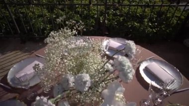 Vazodaki bir buket beyaz çiçek servis masasında duruyor. Yüksek kaliteli FullHD görüntüler