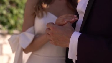 Damat beyaz elbiseli gelinin elini tutuyor, sarılıyor. Yüksek kaliteli FullHD görüntüler