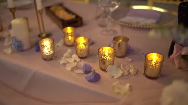 花の花びらが描かれたテーブルの上の燭台でろうそくを燃やす 高品質のフルHd映像 — ストック動画