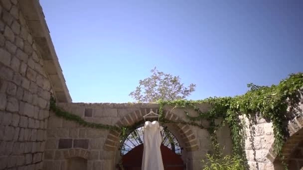 白いウェディングドレスが石造りの建物のアーチ型のドアの上にかかっています 高品質のフルHd映像 — ストック動画