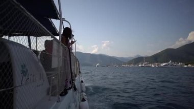 Turistler denizdeki bir gölgelik altında turist katamaranıyla yelken açarlar. Yüksek kaliteli FullHD görüntüler