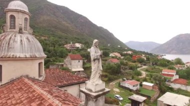 Kilisenin çatısında katlanmış elleri olan Bakire Meryem Heykeli. Prcanj, Karadağ. Yüksek kalite 4k görüntü