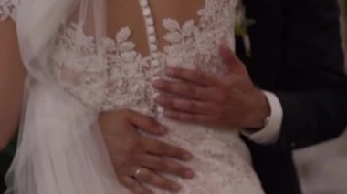 Damat, gelinine nakışlı bir elbiseyle sarıldı. Kırpılmış. Yüksek kaliteli FullHD görüntüler