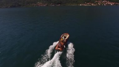 Motorlu yat, dağlık kıyı boyunca beyaz bir köpük izi bırakarak yelken açıyor. Yüksek kalite 4k görüntü