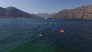 Yat denizde yüzen turistleri geçerek dağların arkasında yüzüyor. Yüksek kalite 4k görüntü
