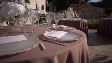 Davetiyeler avludaki masanın üzerindeki tabakların üzerinde duruyor. Yüksek kaliteli FullHD görüntüler