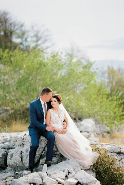 Groom Hugs Bride White Dress Sitting Stones High Quality Photo — Stock Photo, Image