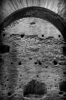Black and white gritty image of the ruined wall of the Colosseum in Rome, Italy.