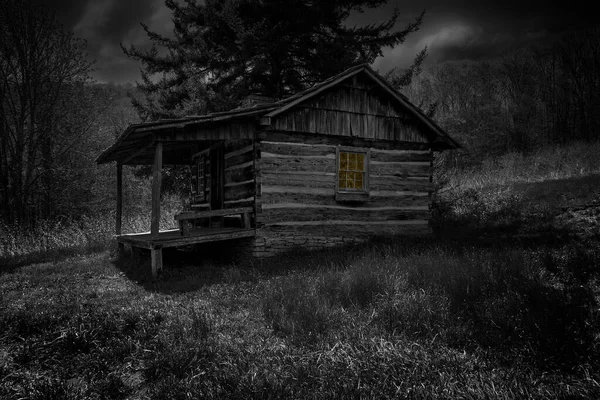 Dark, gritty image of old abandoned house in the woods with a warm glow from inside