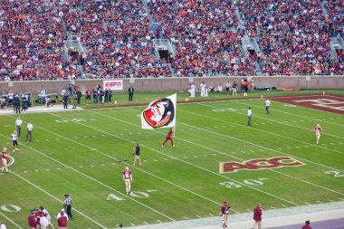 Tallahassee, Florida - 16 Kasım 2013: Florida Eyalet Üniversitesi maskotu Doak Campbell Stadyumu 'ndaki futbol maçında futbol sahasında Seminole Chief Osceola bayrağıyla koşuyor.