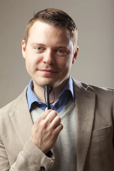 Junger schöner Mann im Anzug mit Brille in der Hand — Stockfoto