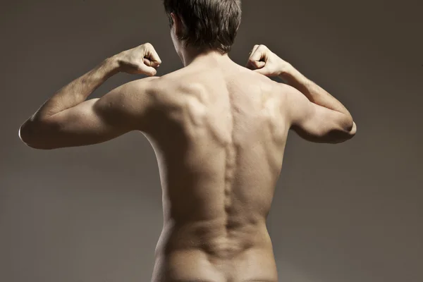 Strong athletic mans back on dark background — Stock Photo, Image