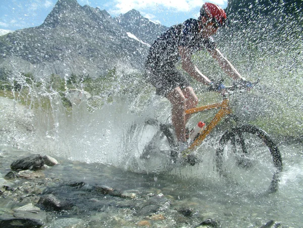 Ciclista de montaña a caballo a través del lecho del río — Foto de Stock