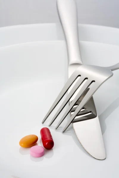 Widelec, nóż i trzy tabletki na talerzu — Zdjęcie stockowe