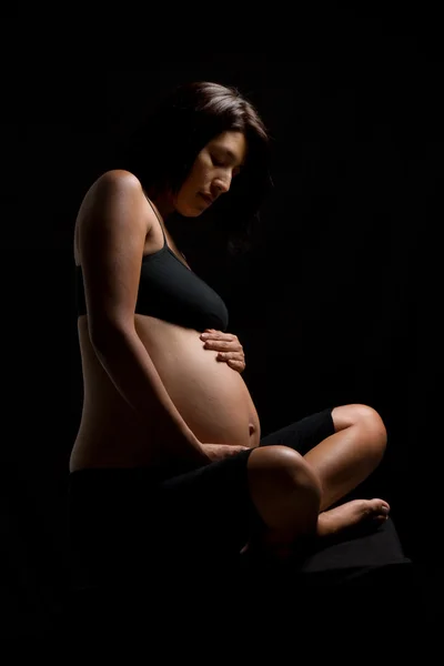 Mulher peruana grávida tocando sua barriga contra o backgro preto — Fotografia de Stock