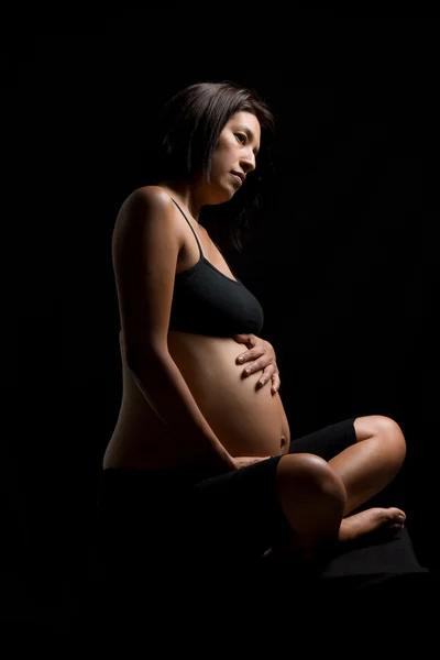 Gravida peruanska kvinnan röra hennes mage mot svart backgro — Stockfoto