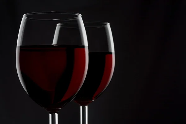 Due bicchieri di vino rosso isolati su fondo nero — Foto Stock