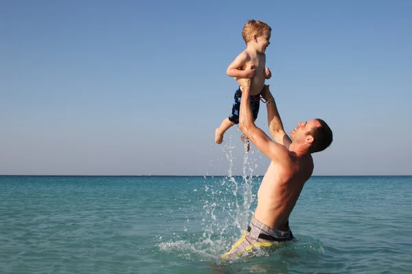 Батько і син грають в океані — стокове фото