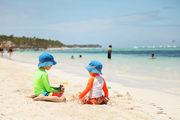 在地处热带的海滩玩沙的两个白人男孩 — 图库照片
