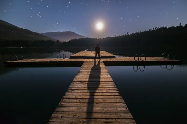 Man tittar på månen på dock i whistler — Stockfoto