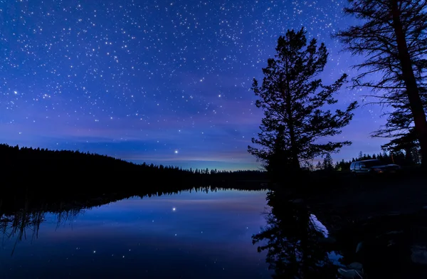 Blauwe nachtelijke hemel langs meer met reflectie — Stockfoto