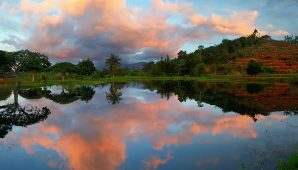 Weerspiegeling van de zonsondergang gekleurde wolken met bomen en heuvels in een lake in borneo, sabah, Maleisië — Stockfoto