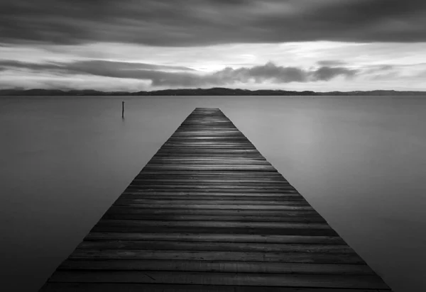 A long exposure shot of a wooden jetty in a gloomy evening — Stock Photo, Image