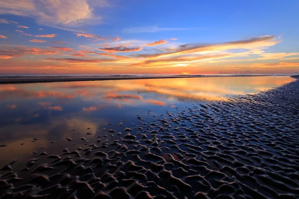 Reflexão do pôr do sol com padrões de areia ondulada — Fotografia de Stock