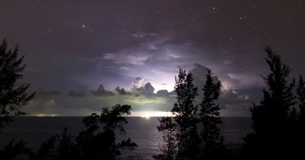 Lightning behind clouds with starry sky — Stock Photo, Image