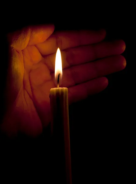 Lidská dlaň a svíčka ve tmě — Stock fotografie