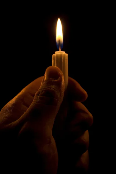 Mão segurando uma vela no escuro — Fotografia de Stock