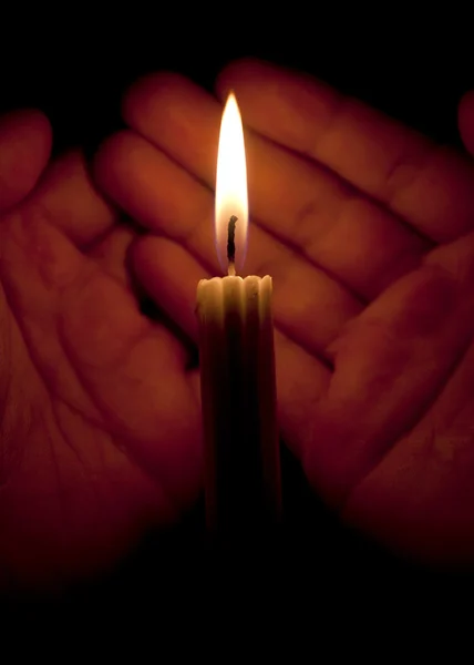 Manos y una vela en la oscuridad — Foto de Stock