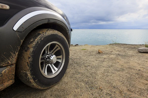 Dirty SUV car tire with gloomy sky — Stock Photo, Image