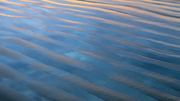 Textura de arena ondulada con colores de puesta de sol reflejados —  Fotos de Stock