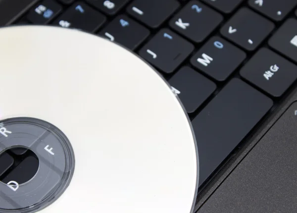 Kompaktní disk na klávesnici notebooku — Stock fotografie