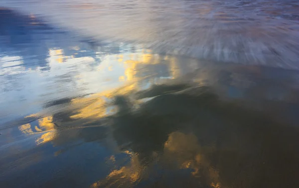 Fargerik sky reflektert i våt sand – stockfoto