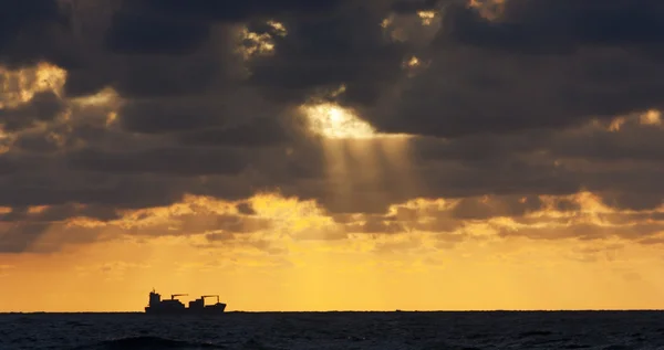 Silueta de un barco al atardecer con rayos de sol —  Fotos de Stock